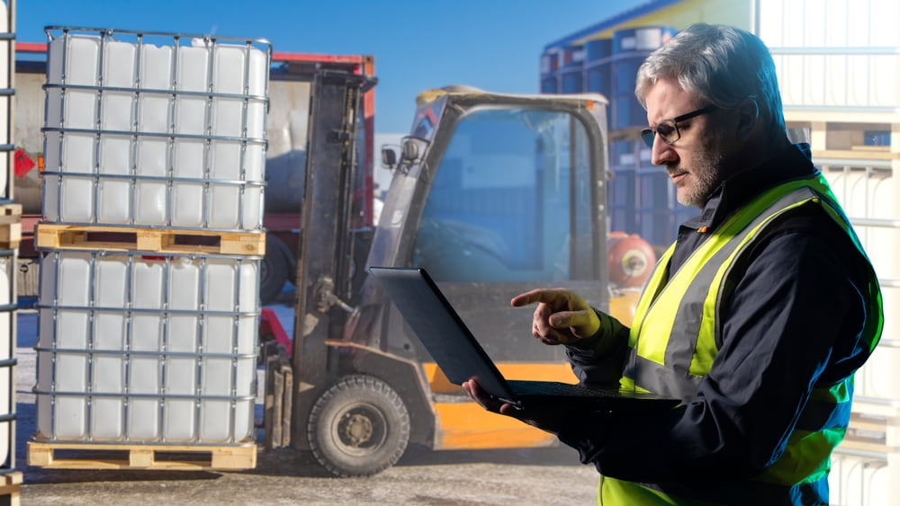 Worker with laptop inspects forklift